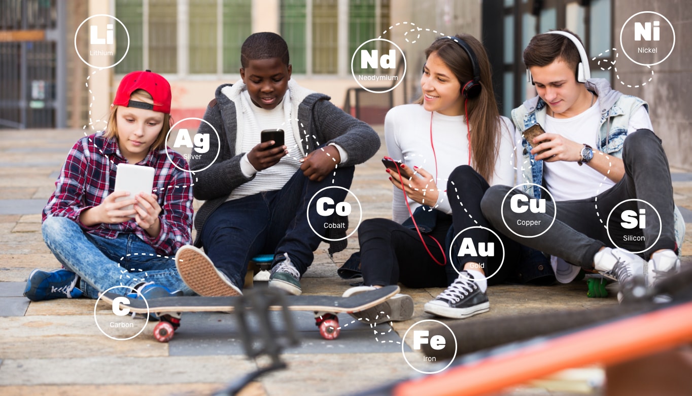 Image of four teenagers sitting outdoors playing on and listening to music generated from mobile devices. Two teens are wearing headphones. Lithium and silver are used in tablets, carbon in shoes. Cobalt, gold and copper are used in mobile phones, iron in skateboard axels, silicon in watches, and neodymium and nickel in headphones.